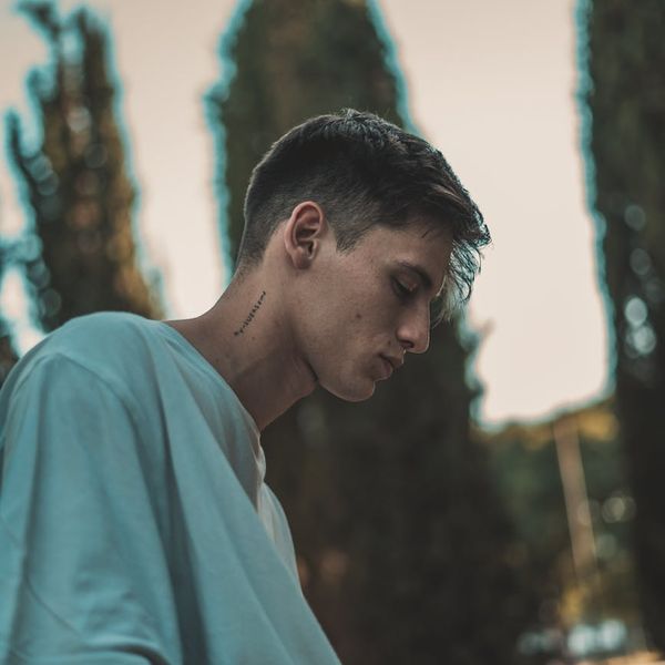 Man stretching outdoors with a serene natural background and a calm expression.